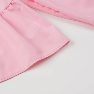 Detailed view of pink blouse fabric featuring delicate ruffles and pleated edge details
