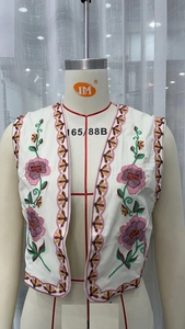 Close-up of floral embroidery on a white vintage vest with pink and purple flowers