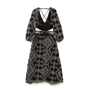 Détail de broderie géométrique blanche et taille ajourée sur une robe midi noire