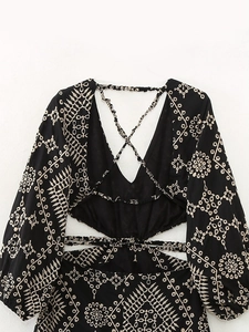 Détail de la robe noire avec broderie florale dorée et découpe élégante à la taille