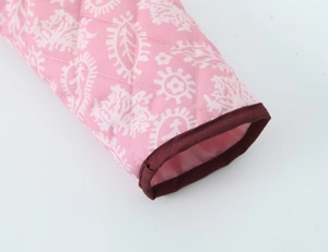 Dettaglio della giacca in cotone trapuntato rosa con stampe paisley bianche e bordi marroni
