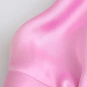 Macro della consistenza liscia e della lucentezza setosa del tessuto di raso rosa