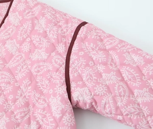 Dettaglio della giacca trapuntata rosa con motivi paisley bianchi e piping a contrasto