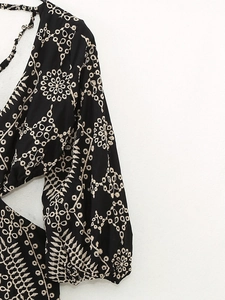Détail de robe noire brodée avec manches lanternes et design ajouré à la taille