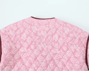 Dettaglio macro del tessuto trapuntato rosa con stampa a foglie bianche e bordo bordeaux