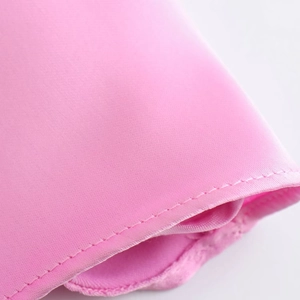 Dettaglio ravvicinato delle cuciture e della trama satinata rosa dell'abito con riflessi