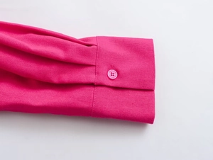 Close-up of bright pink shirt cuff with single button and pleated sleeve details