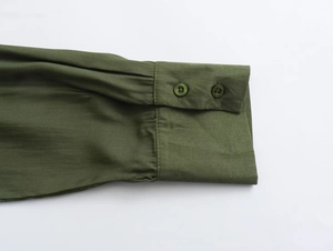 Detail of army green shirt cuff with two buttons and refined stitching texture