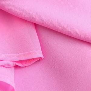 Dettaglio macro del tessuto satinato rosa acceso con cuciture di precisione sui bordi