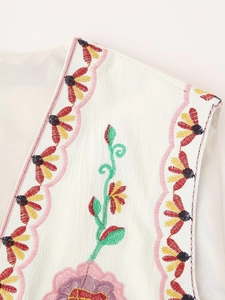 Detailed close-up of colorful floral embroidery and wave edges on a white vest