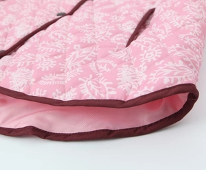 Dettaglio macro del tessuto trapuntato paisley rosa con bordo a contrasto e bottone