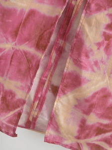Detail of pink tie-dye fabric showing high-quality overlock stitching and woven texture