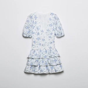 Detail of V-neck floral dress with lace patchwork waist and tiered ruffle hemline