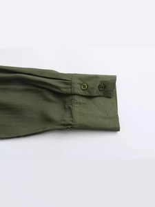 Detail of dark green Y2K loose shirt featuring textured fabric and double-button cuffs