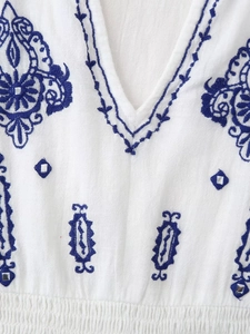 Détail de broderie ethnique bleue et miroirs sur chemise blanche en coton à col en V