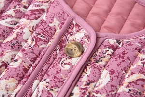 Detailed macro view of quilted floral jacket with marble button and purple edge binding