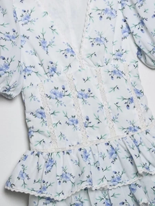 Detail of floral V-neck dress with white lace trim and blue flower pattern