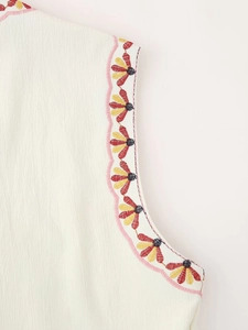 Detail of scalloped edges with colorful flower embroidery on crepe fabric vest