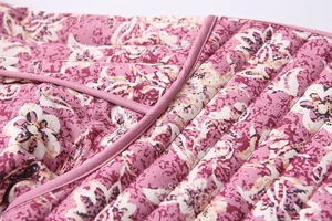 Close-up of pink floral quilted fabric with neat parallel stitching for winter jackets