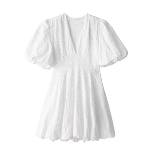 Détail d'une robe blanche à manches bouffantes avec texture florale 3D et col en V