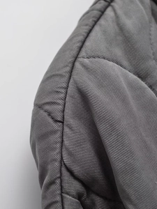 Detailed macro view of dark grey quilted fabric with twill texture and diamond stitching