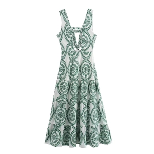 Detailed view of white backless dress with green embroidery and ruffled tiered skirt