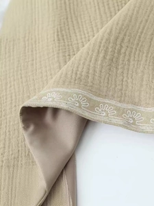 Gilet court beige à broderie florale avec coutures contrastées et tissu texturé doux