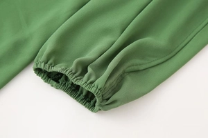 Détail du poignet élastique vert herbe montrant la texture du tissu maille sur la robe