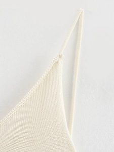 Close-up of cream knit dress detailing fine stitching and delicate spaghetti straps