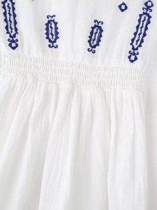 Détails de broderies géométriques et taille élastique smockée sur chemisier en lin blanc