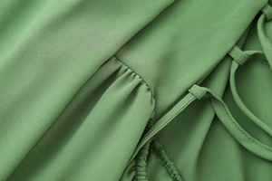 Gros plan sur le tissu en tulle vert sauge avec volants et bretelles à lacets de la robe