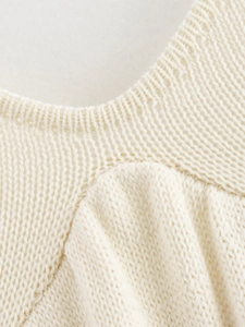 Detailed close-up of cream knit dress neck stitching with delicate mesh and ribbed texture