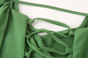 Détail du laçage croisé au dos d'une mini robe en maille transparente vert herbe
