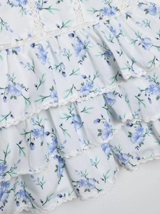 Detail of blue floral print ruffles and white lace trim on a summer tiered dress