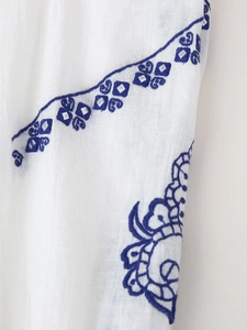 Détail macro d'une broderie bleue sur tissu en coton blanc au motif ethnique