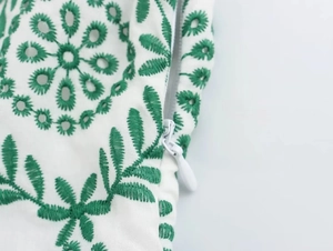 Close-up of green floral embroidery and white invisible zipper on summer dress fabric