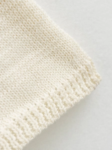 Close-up detail of cream knitted dress showing smooth jersey and ribbed texture