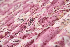 Close-up of pink floral quilted fabric with vertical stitching and padded texture
