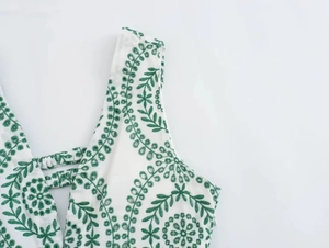 Close-up of green floral embroidery on white fabric with hidden zipper detail