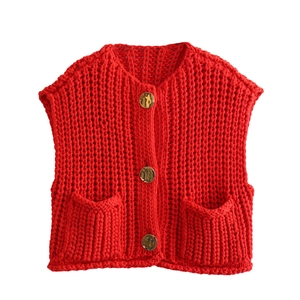 Detail of red chunky knit vest featuring large golden metal buttons and ribbed texture