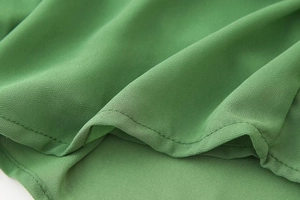 Macro d'un tissu en maille verte montrant les doubles coutures et la texture fine