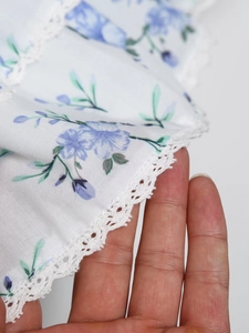 Close-up of white floral summer dress featuring delicate lace trim and v-neck detail