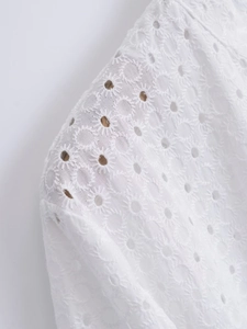 Close-up detail of white Broderie Anglaise embroidery on high-quality cotton dress sleeve