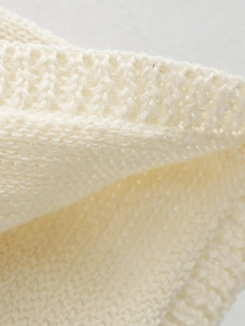 Macro shot of cream knit dress fabric showing soft wool blend texture and fine ribbing