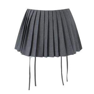 Detail view of high-waisted dark grey pleated skirt with decorative hanging ribbons
