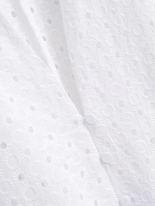 Detailed macro view of white eyelet embroidery lace fabric and matching covered buttons