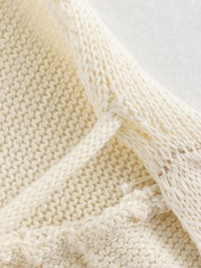 Close-up of cream knit dress fabric showing intricate stitch textures and soft woven details