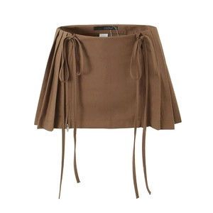 Detail of brown pleated mini skirt featuring decorative side ribbons and metal zipper
