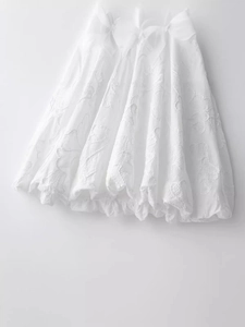 Robe blanche avec broderie florale et grands nœuds décoratifs dans une silhouette bouffante