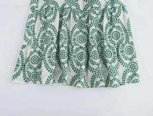 Detail of white tiered skirt hem featuring green floral embroidery and layered ruffles